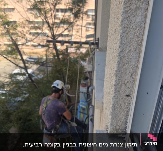 עובד בגובה בגלישת סנפלינג לצד חזית בניין מגורים